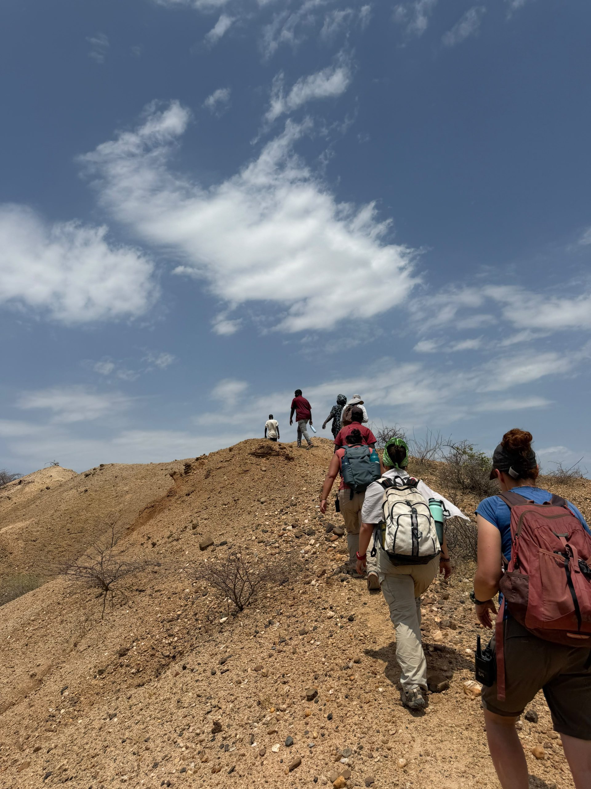 Students hiking up hill in arid desert of Kenya.